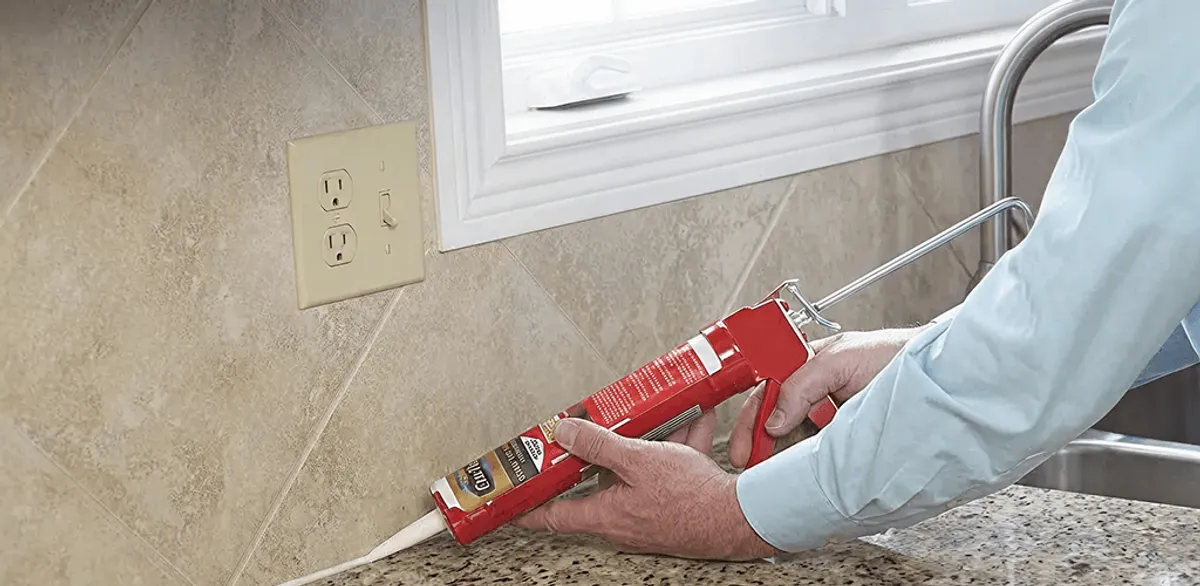 Handyman applying caulk along a kitchen backsplash and countertop seam in Houston, TX