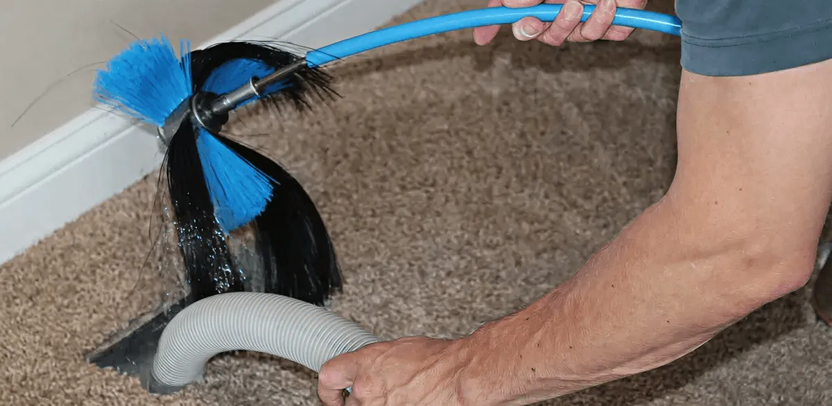 Dryer vent cleaning technician brushing lint from a vent line in Houston, TX